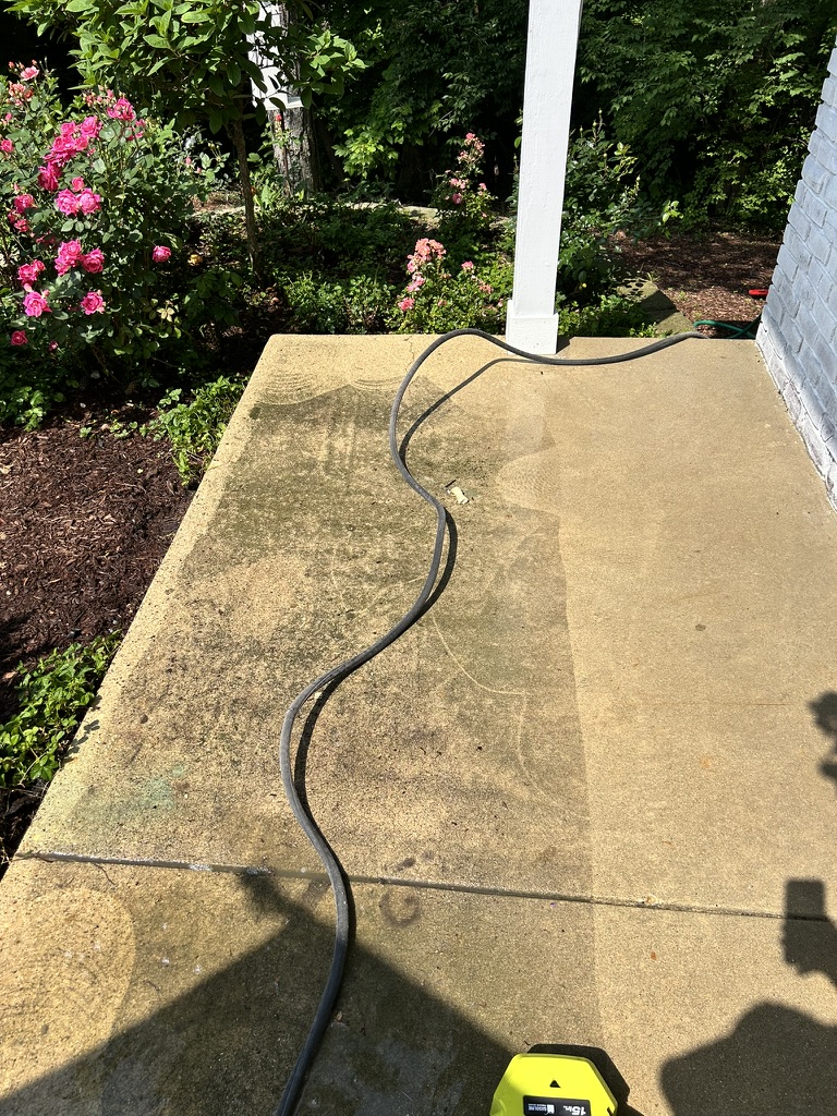 Pressure washed concrete patio showing clean surface next to algae-stained area